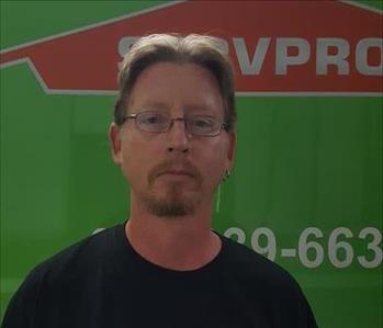 Man with goatee in front of green trailer 